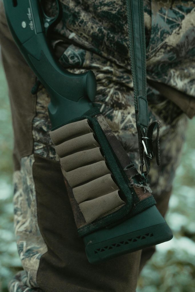 Close-up of a rifle with ammunition holder and camouflage clothing, perfect for hunting themes.