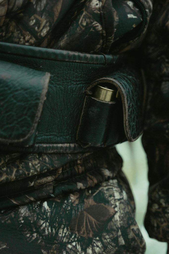 Detailed view of a camouflage belt featuring a leather ammo holder for hunting gear.