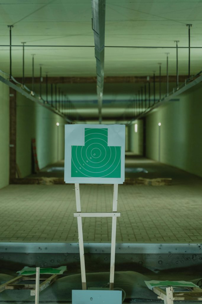 Green shooting target in an indoor range setting, with perspective focus down the range lanes.